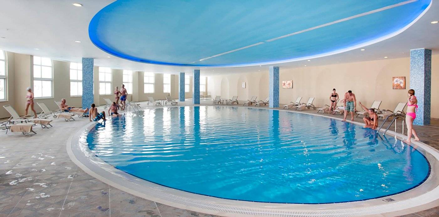 Hallenbad im Defne Defnem Hotel mit blauer Decke und blauem Wasser.