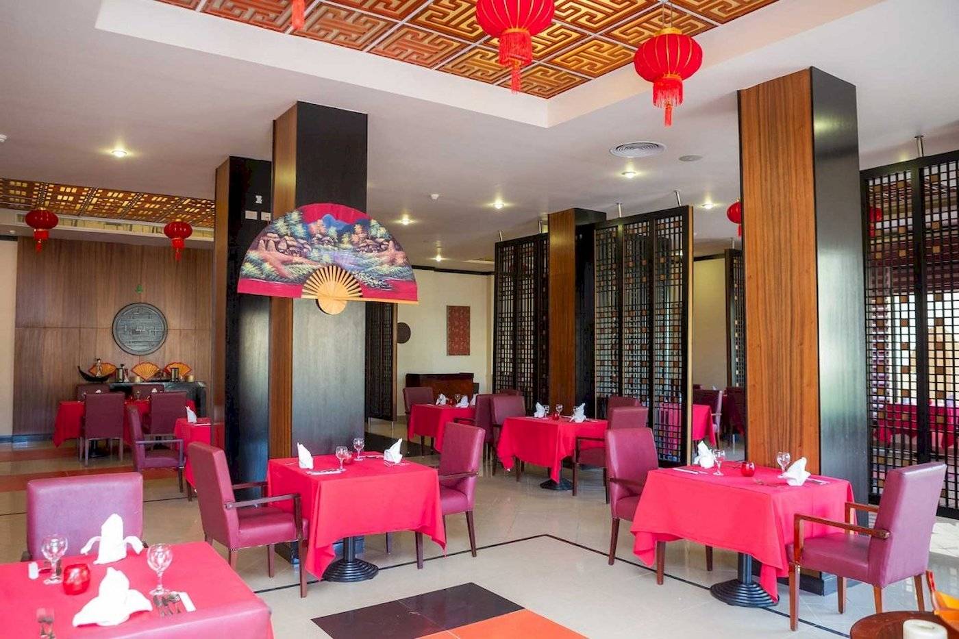 Restaurant im Stella Gardens Resort & Spa Makadi Bay mit roten Tischen und Stühlen.