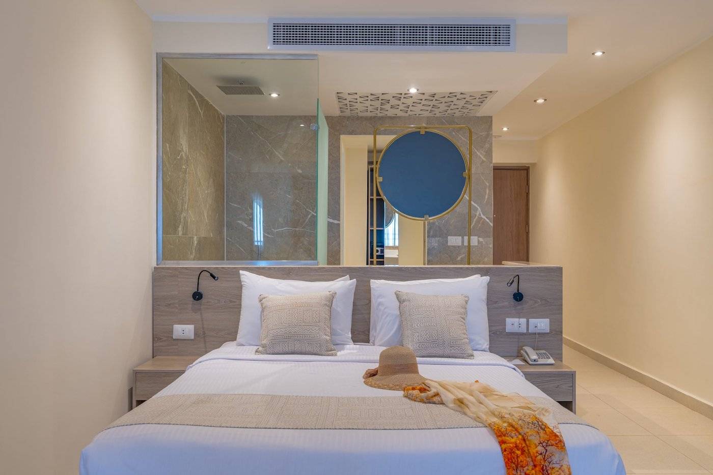 Schlafzimmer im Three Corners Equinox Beach Resort mit einem Bett, Kissen, einem Hut und einer Decke.