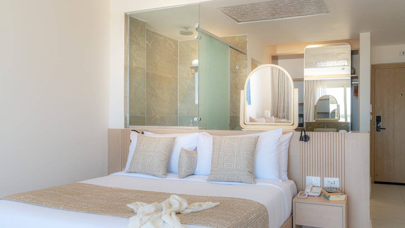 Schlafzimmer im Three Corners Equinox Beach Resort mit Bett und Badezimmerspiegel
