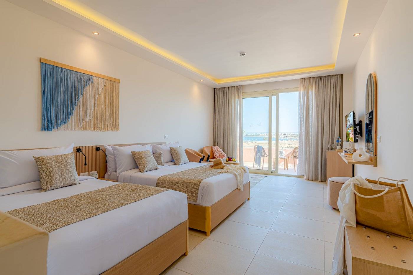 Zwei Betten in einem Hotelzimmer im Three Corners Equinox Beach Resort mit Blick auf das Meer.
