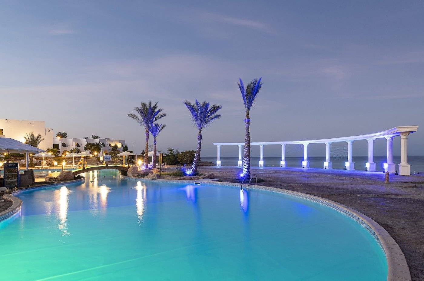 Ein Pool im Three Corners Equinox Beach Resort bei Nacht, beleuchtet von blauen Lichtern.