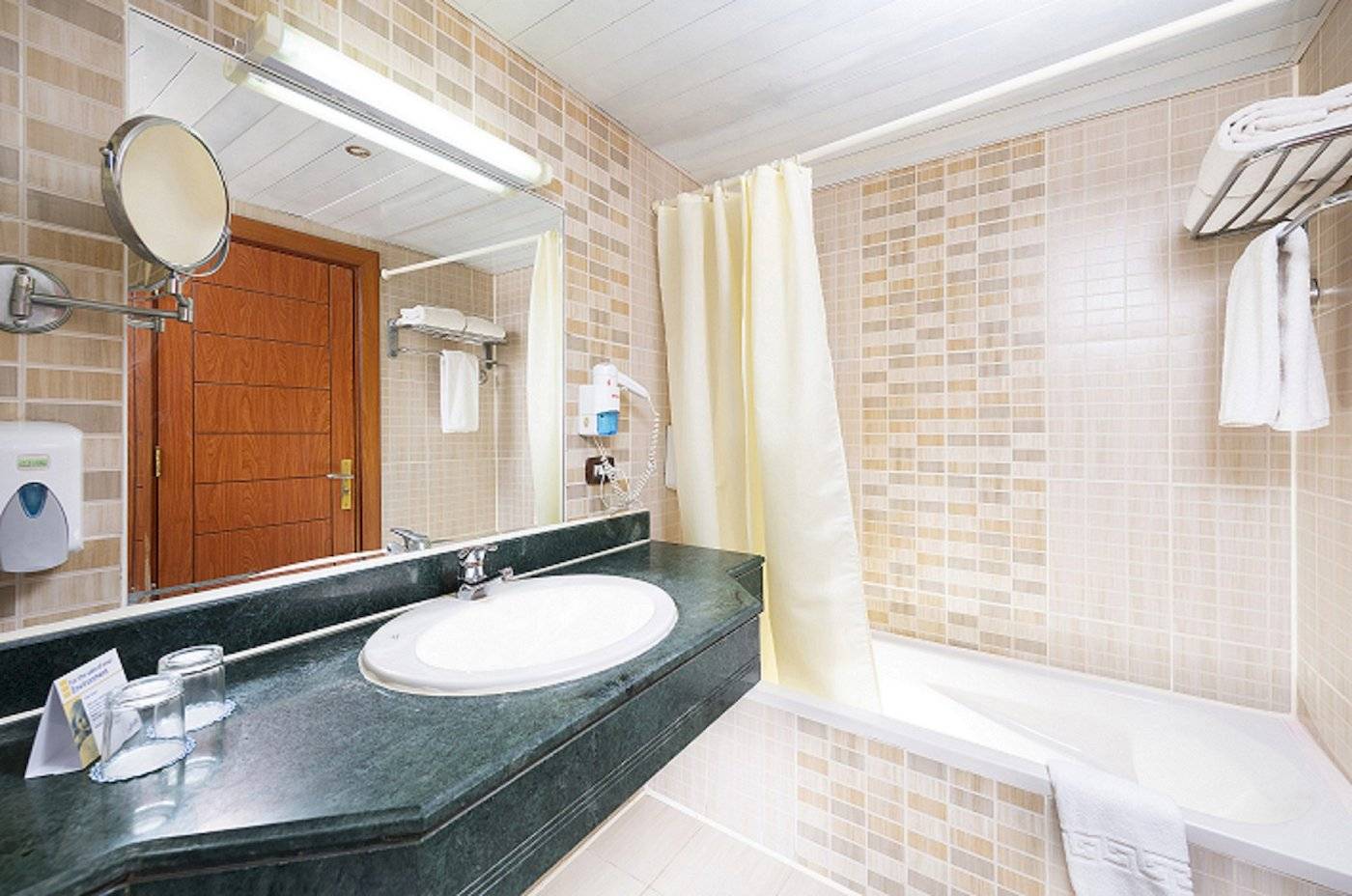 Badezimmer im Three Corners Equinox Beach Resort Hotel mit Waschbecken, Spiegel und Badewanne.