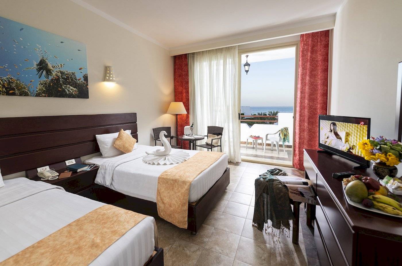 Doppelzimmer im Three Corners Equinox Beach Resort mit Meerblick, zwei Betten, Fernseher, und Balkon.