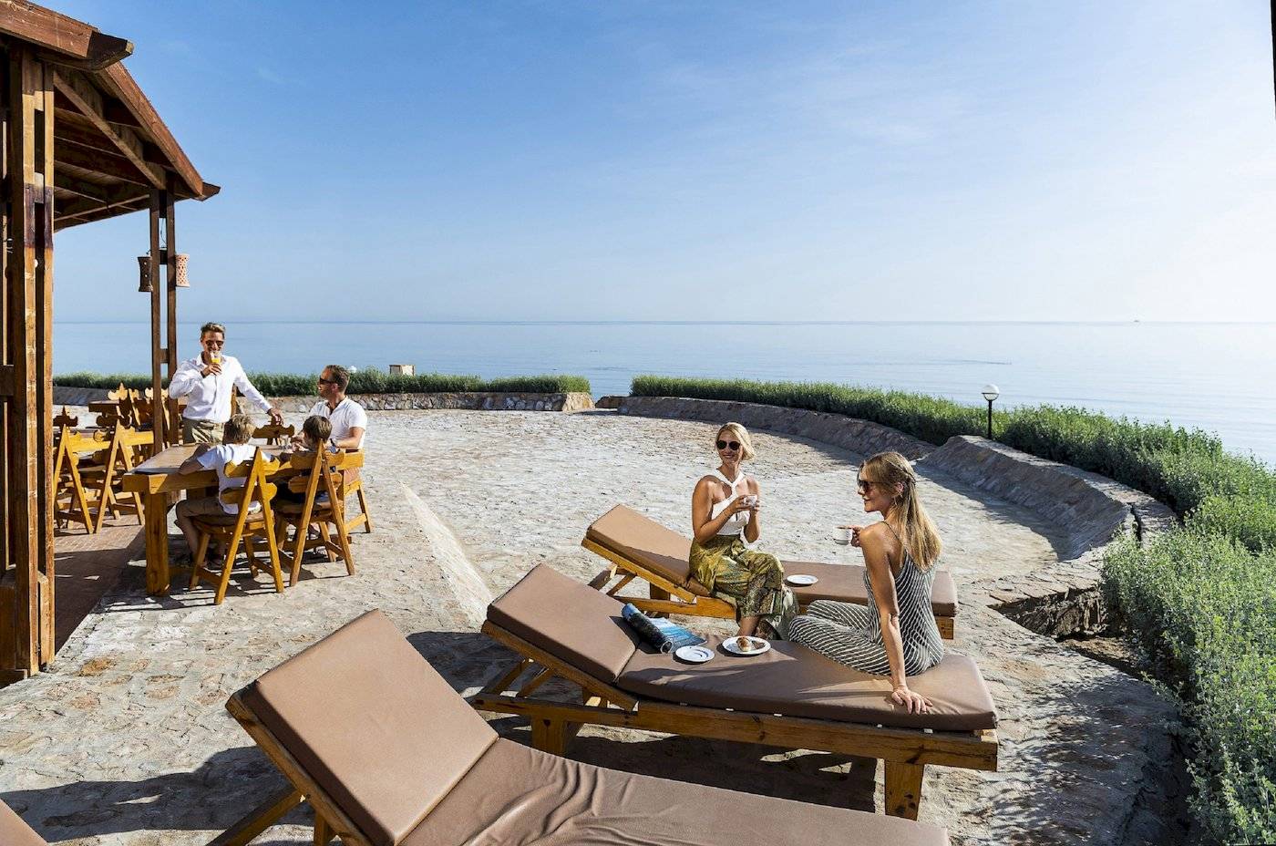 Gäste des Three Corners Equinox Beach Resorts auf einer Terrasse mit Blick auf das Meer.