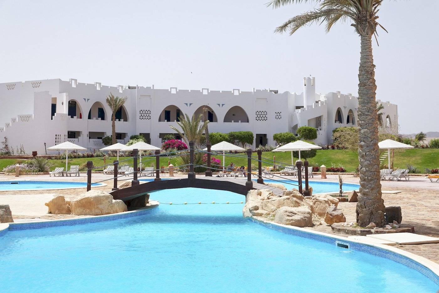 Außenpool im Three Corners Equinox Beach Resort mit Brücke und weißen Gebäuden im Hintergrund.