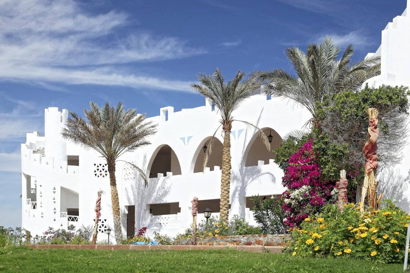 Außenansicht des Three Corners Equinox Beach Resorts mit weißen Gebäuden und Palmen