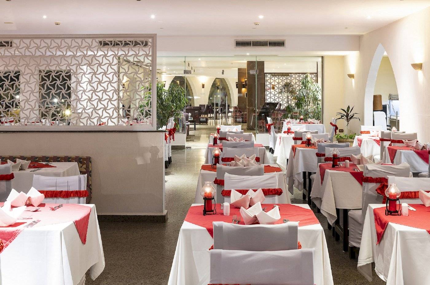 Restaurant-Innenbereich des Three Corners Equinox Beach Resorts mit gedeckten Tischen und roten Tischdecken.