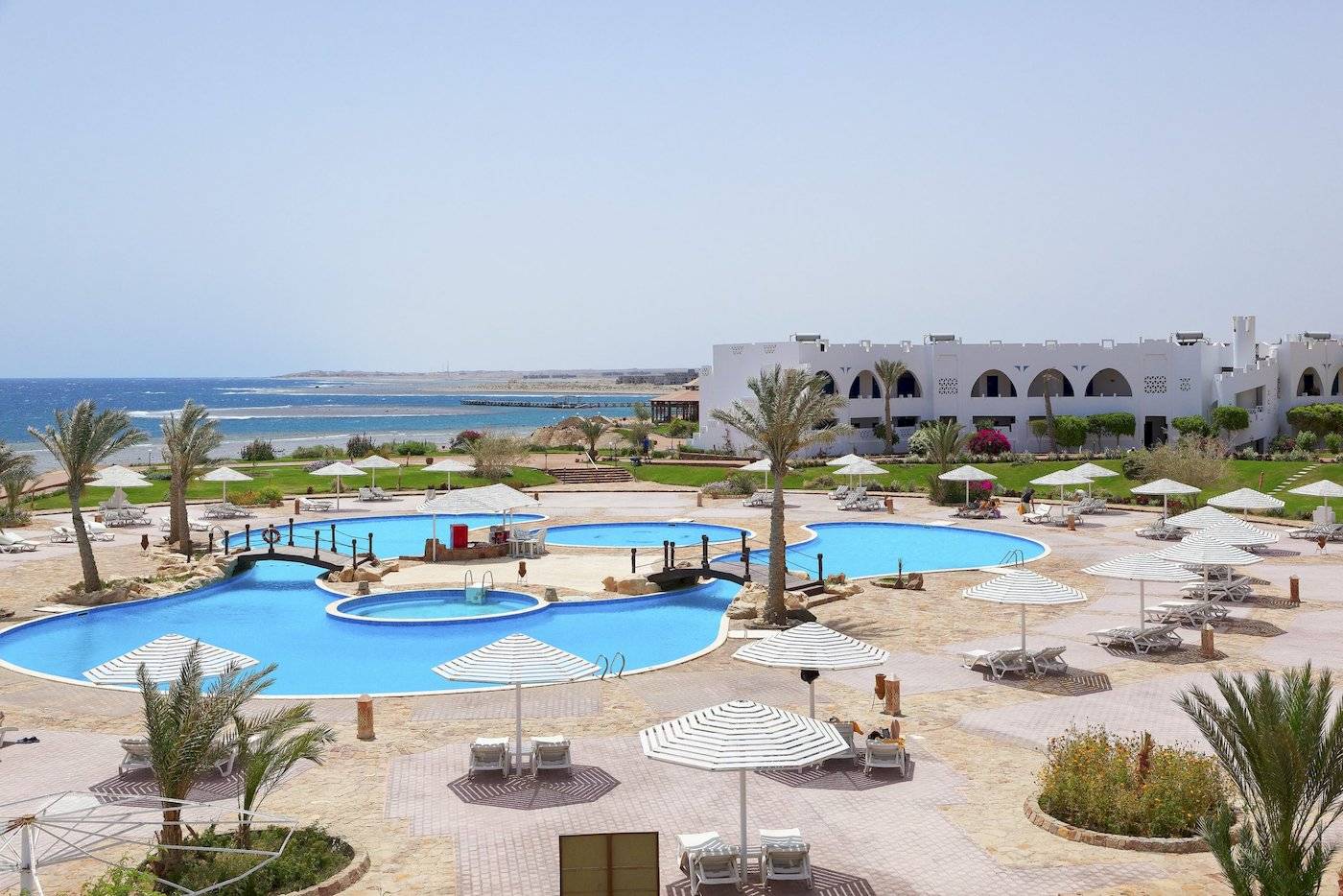 Luftaufnahme des Three Corners Equinox Beach Resorts mit Swimmingpools, Sonnenschirmen und Lounge-Stühlen.