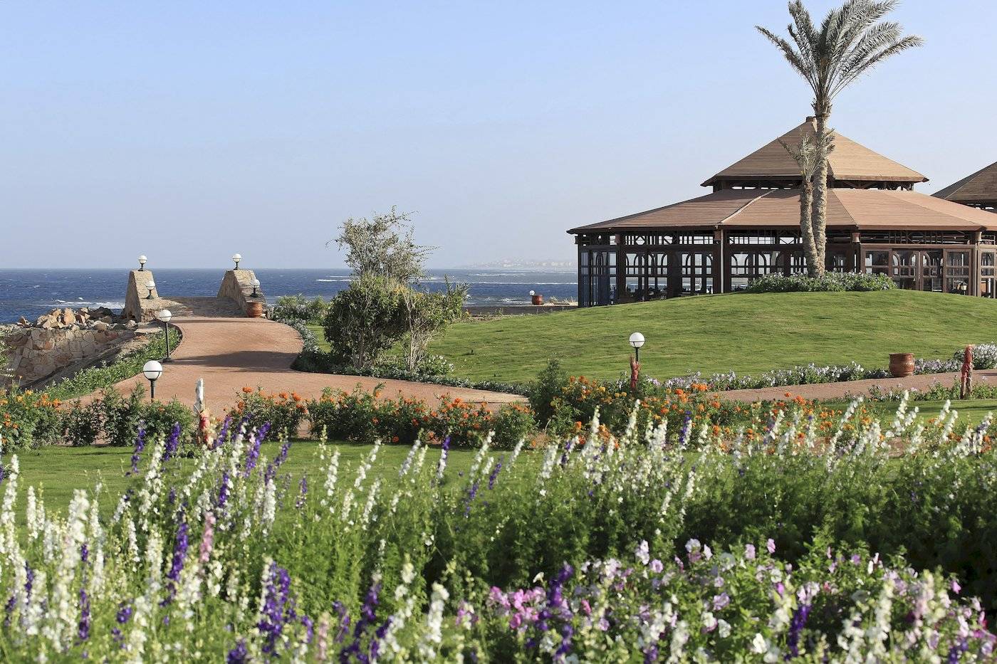 Garten mit Blumen und Gehweg zum Three Corners Equinox Beach Resort.