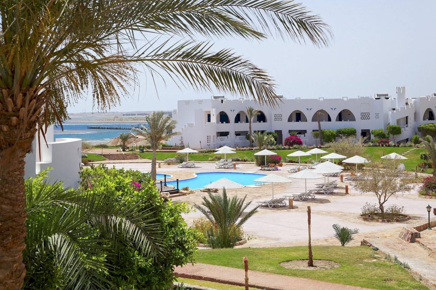 Außenbereich des Three Corners Equinox Beach Resorts mit Pool und Liegen.