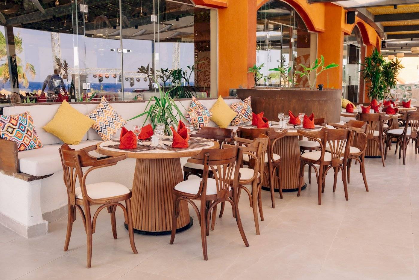 Innenbereich des Restaurants im Three Corners Happy Life Beach Resort mit runden Tischen und Stühlen.