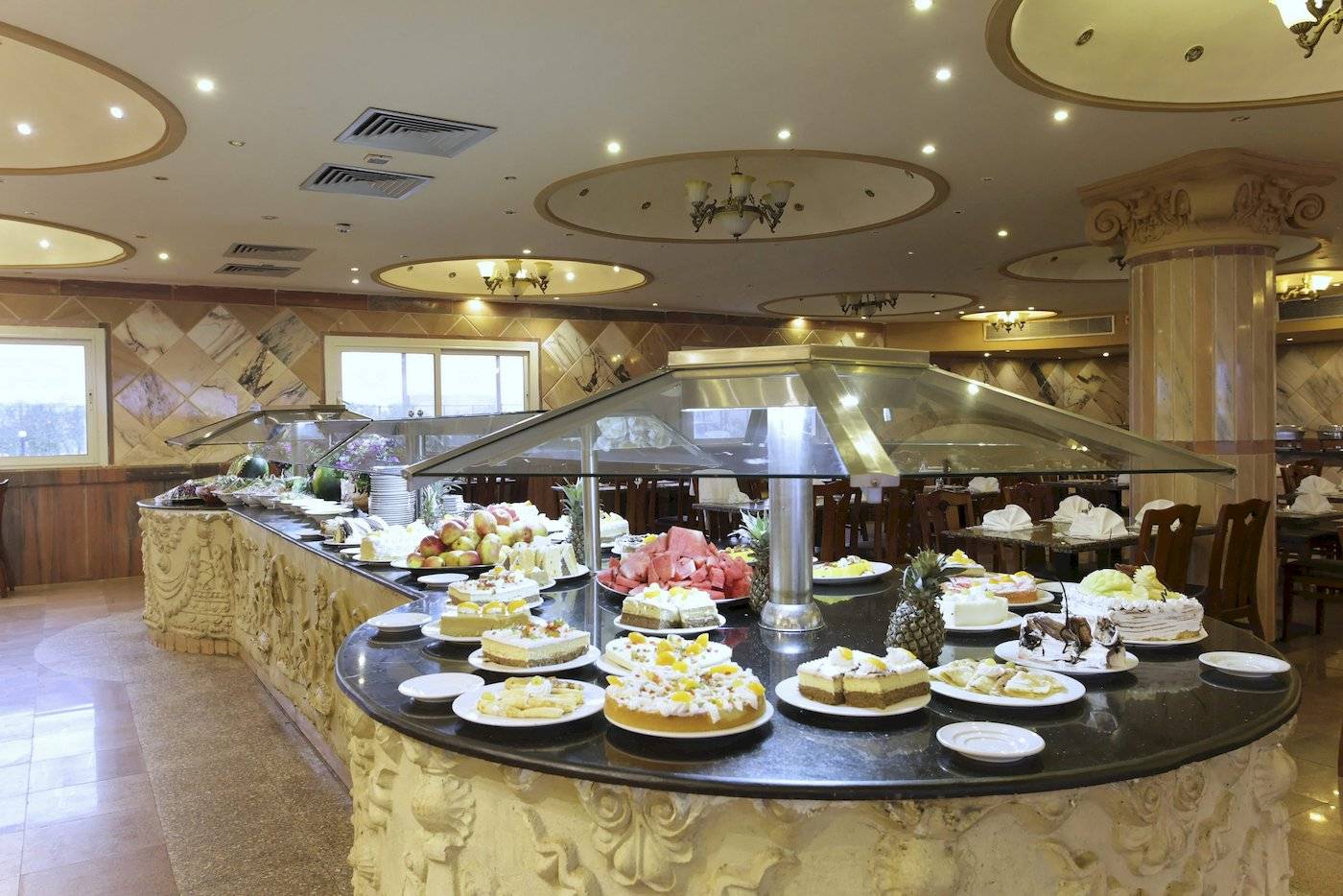 Buffet-Tisch im Three Corners Happy Life Beach Resort mit verschiedenen Kuchen und Obst.