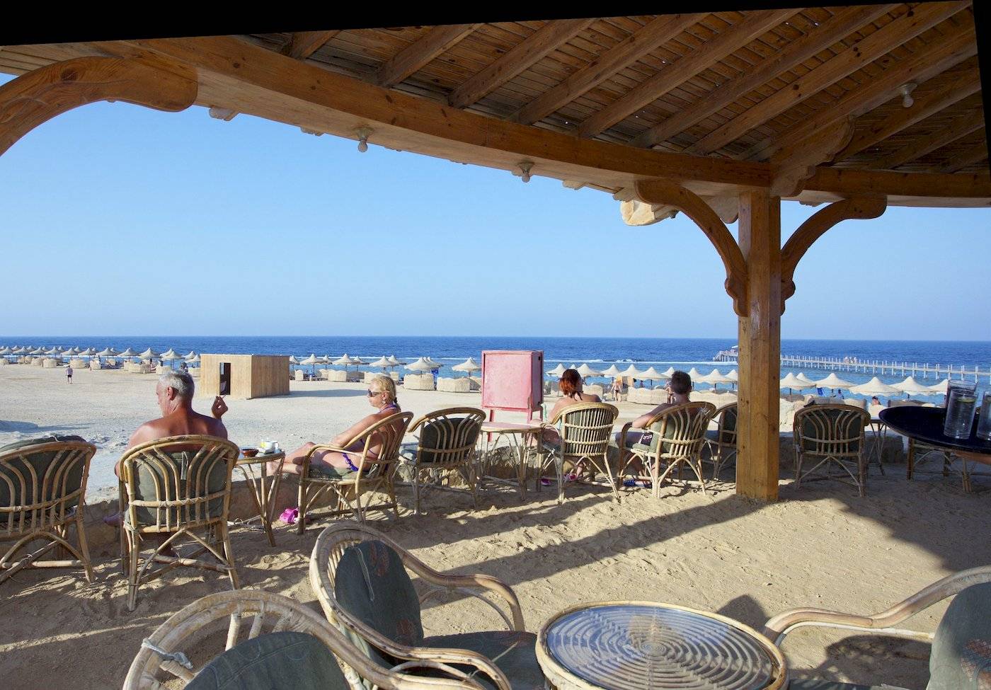 Gäste sitzen unter einem Pavillon am Strand des Three Corners Happy Life Beach Resorts.
