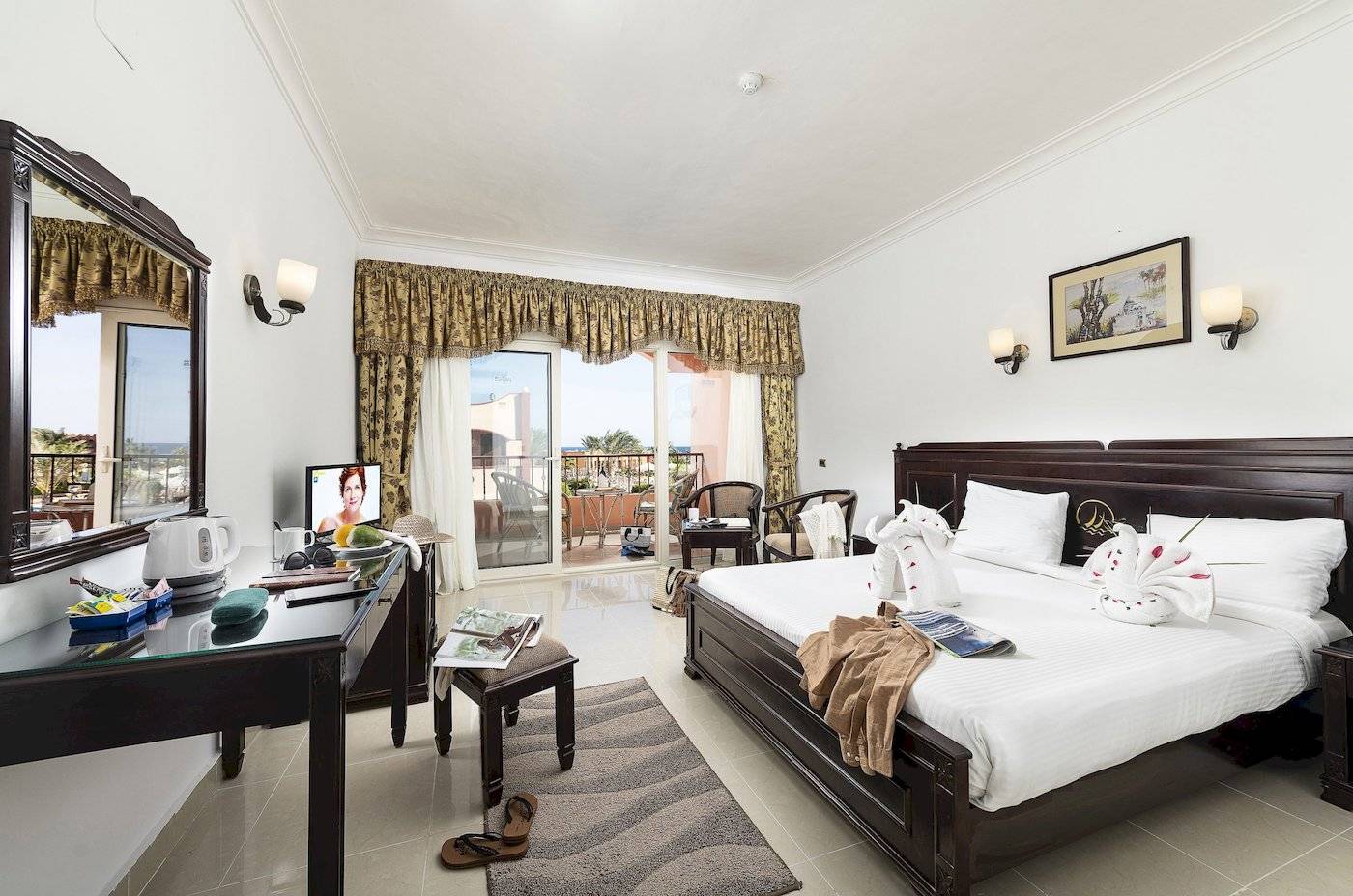 Hotelzimmer des Three Corners Happy Life Beach Resort mit Bett, Fernseher und Balkon.