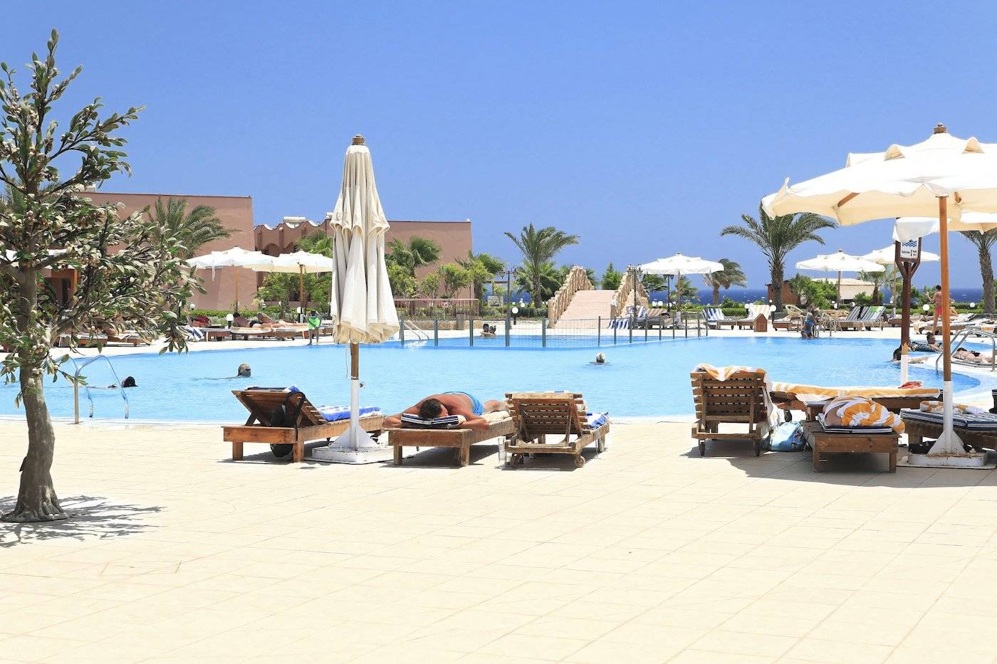 Poolbereich im Three Corners Happy Life Beach Resort mit Sonnenliegen und Sonnenschirmen