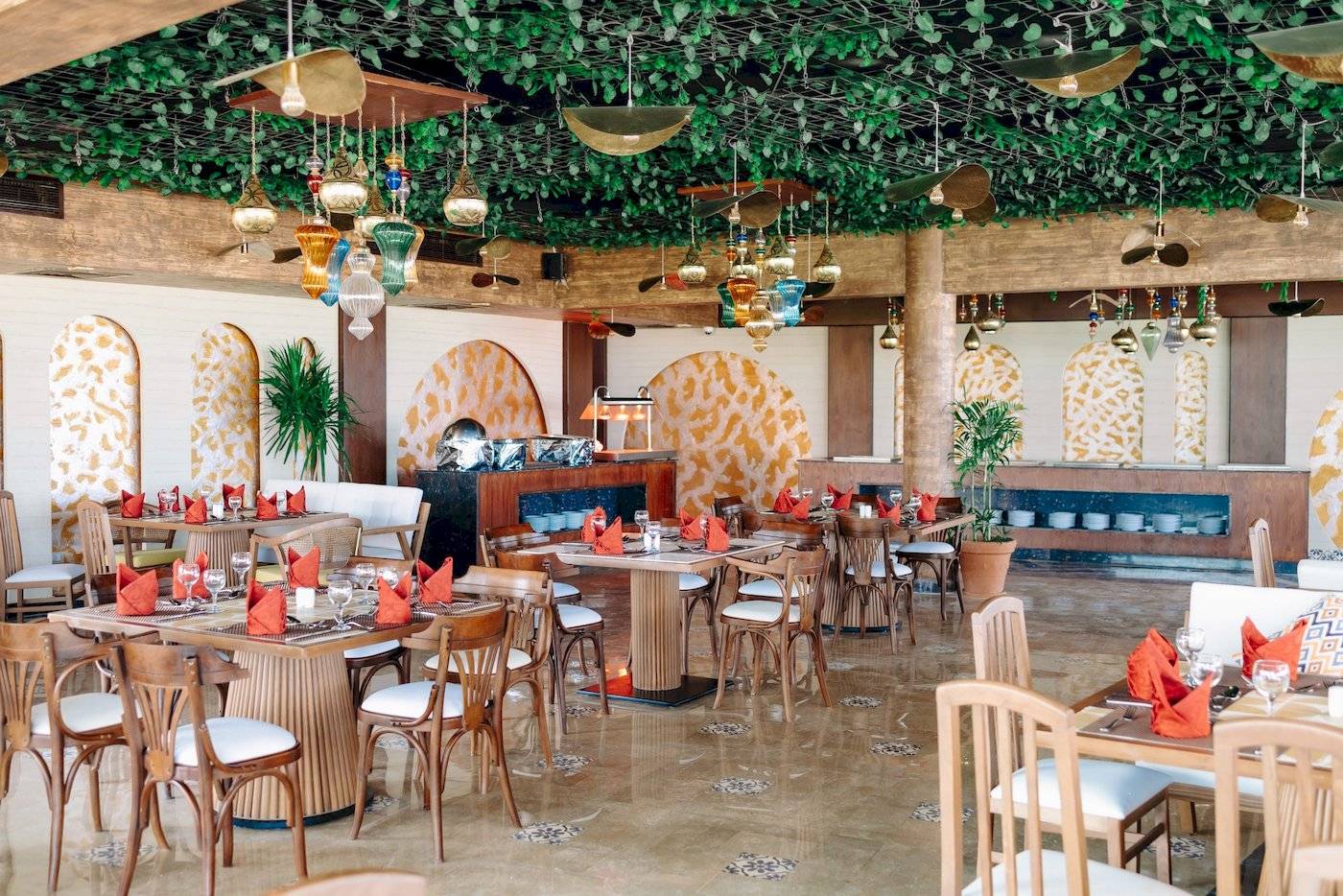 Restaurant im Three Corners Happy Life Beach Resort mit Tisch und Stühlen, geometrischen Wandmustern und dekorativen Lampen.