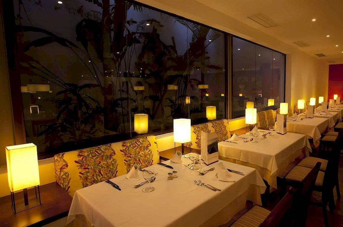 Innenansicht des Restaurants im Costa Calero Thalasso & Spa Hotel bei Nacht mit gedeckten Tischen und warmem Licht.