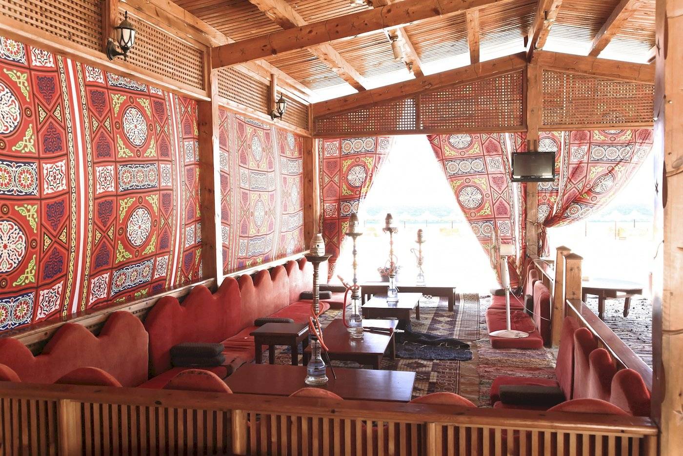 Innenbereich des Three Corners Happy Life Beach Resorts mit roten Sofas, Holztischen und bunten Wandbehängen.