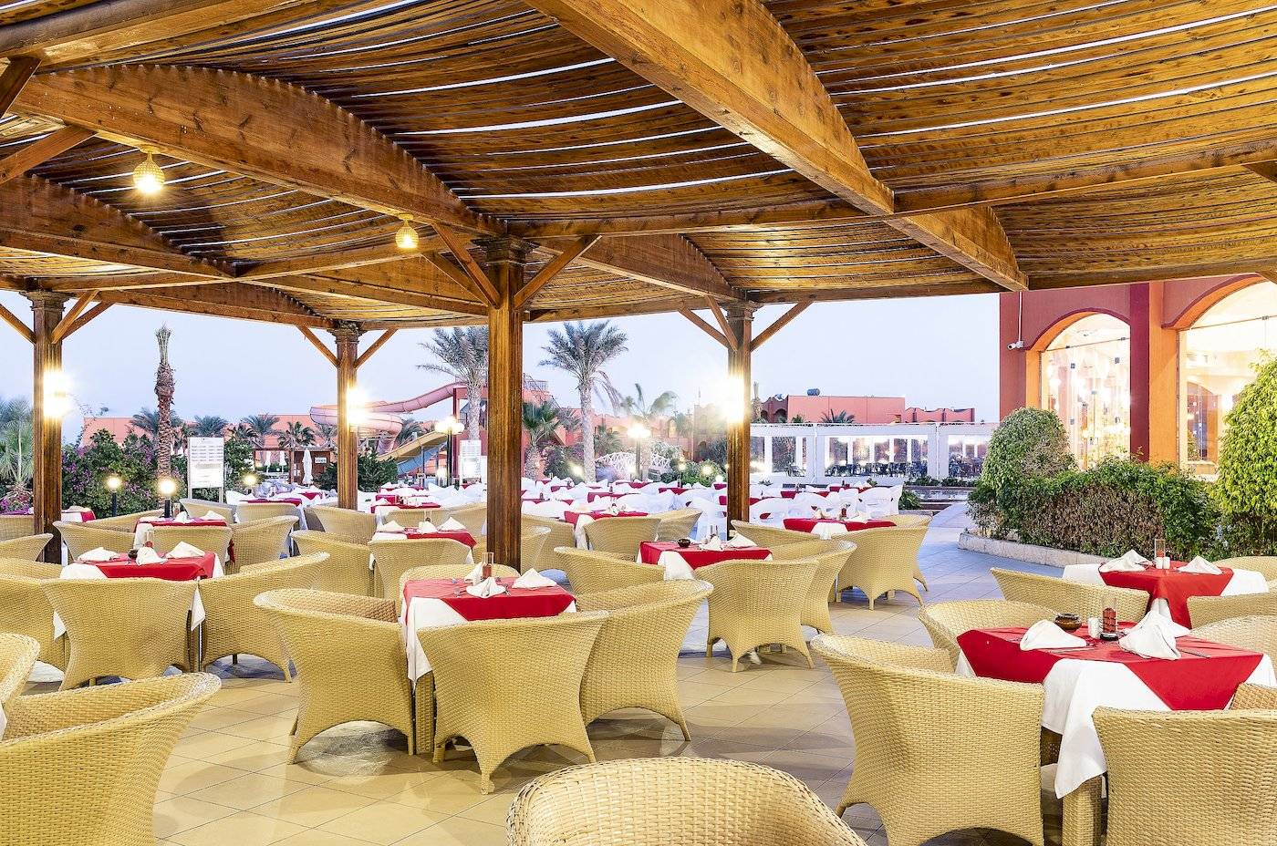 Restaurant im Three Corners Happy Life Beach Resort mit vielen gedeckten Tischen und Stühlen.