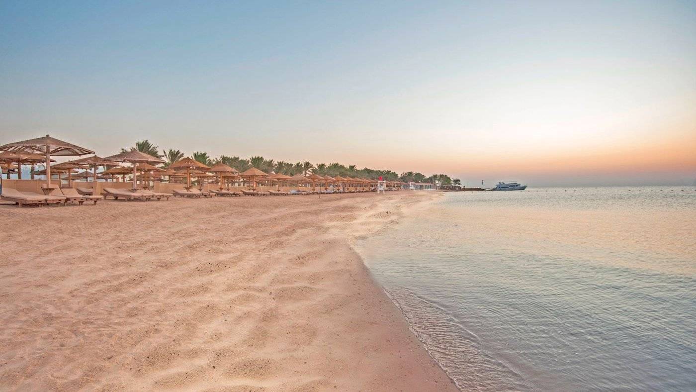 Sonnenuntergang am Strand des SUNRISE Royal Makadi Resort mit vielen Sonnenschirmen