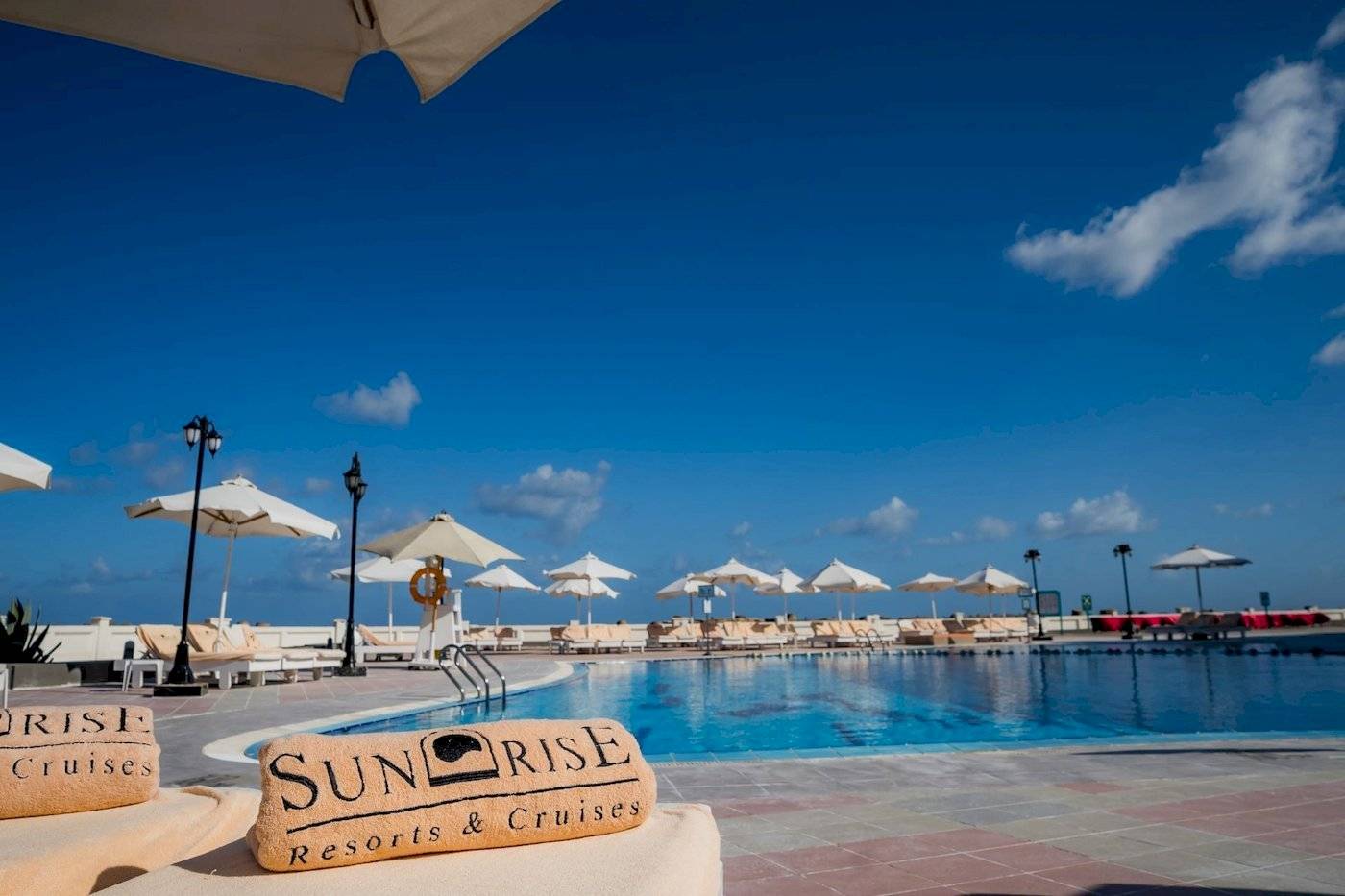 Poolbereich des Sunrise Royal Makadi Resorts mit Liegestühlen und Sonnenschirmen.