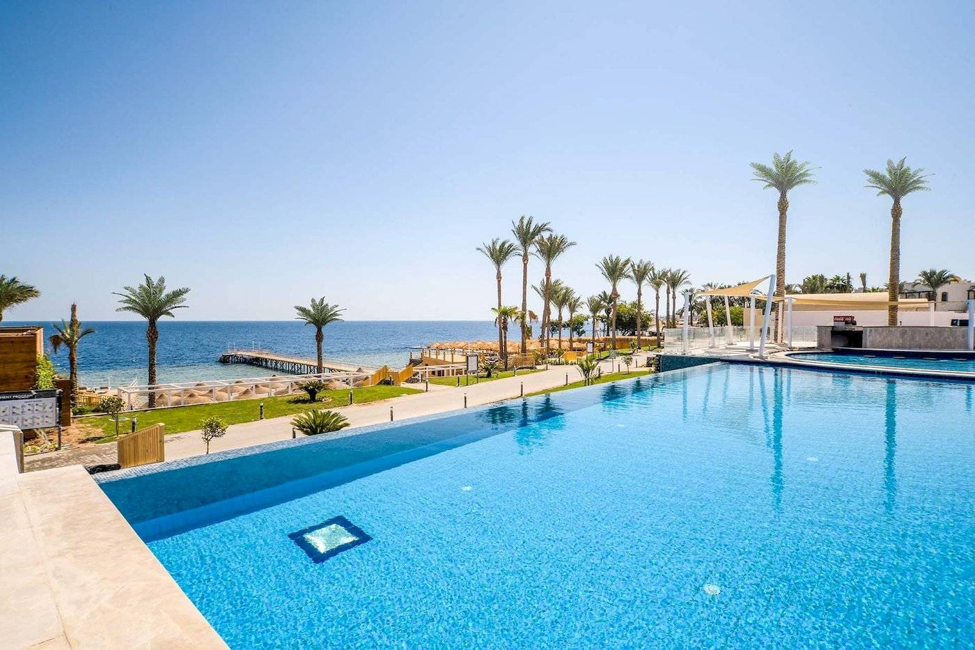 Außenpool am Sunrise Royal Makadi Resort mit Blick auf das Meer und Palmen