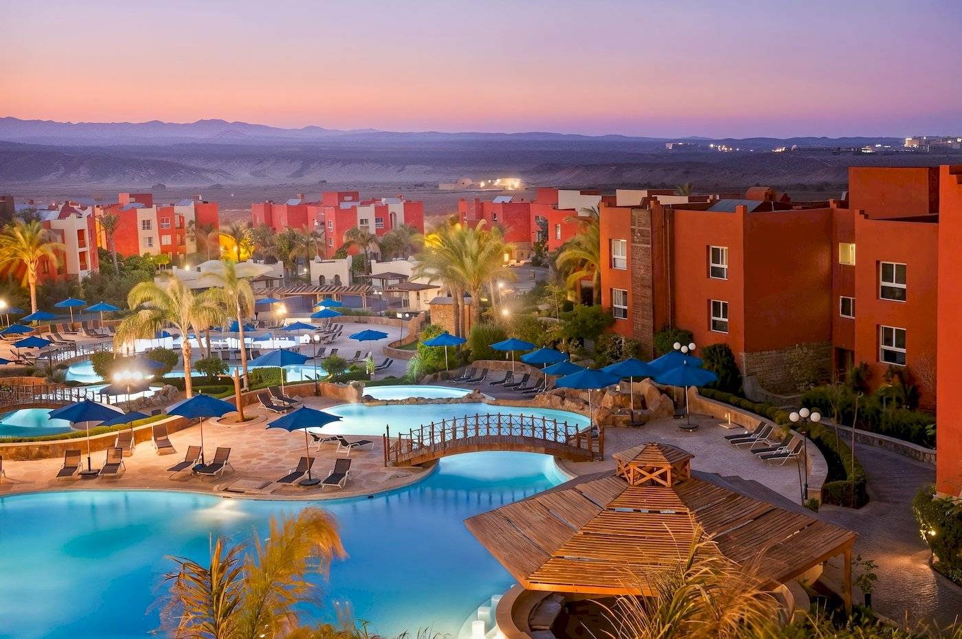 Luftaufnahme des Sunrise Royal Makadi Resorts mit Swimmingpools, Liegestühlen und roten Gebäuden.