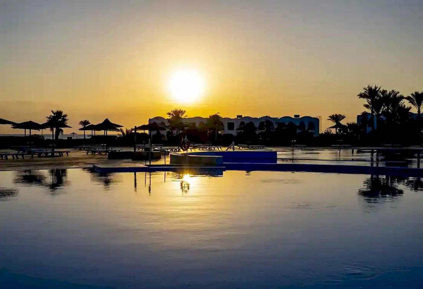 Sonnenuntergang am Gorgonia Beach Resort mit Swimmingpool und Palmen im Hintergrund.