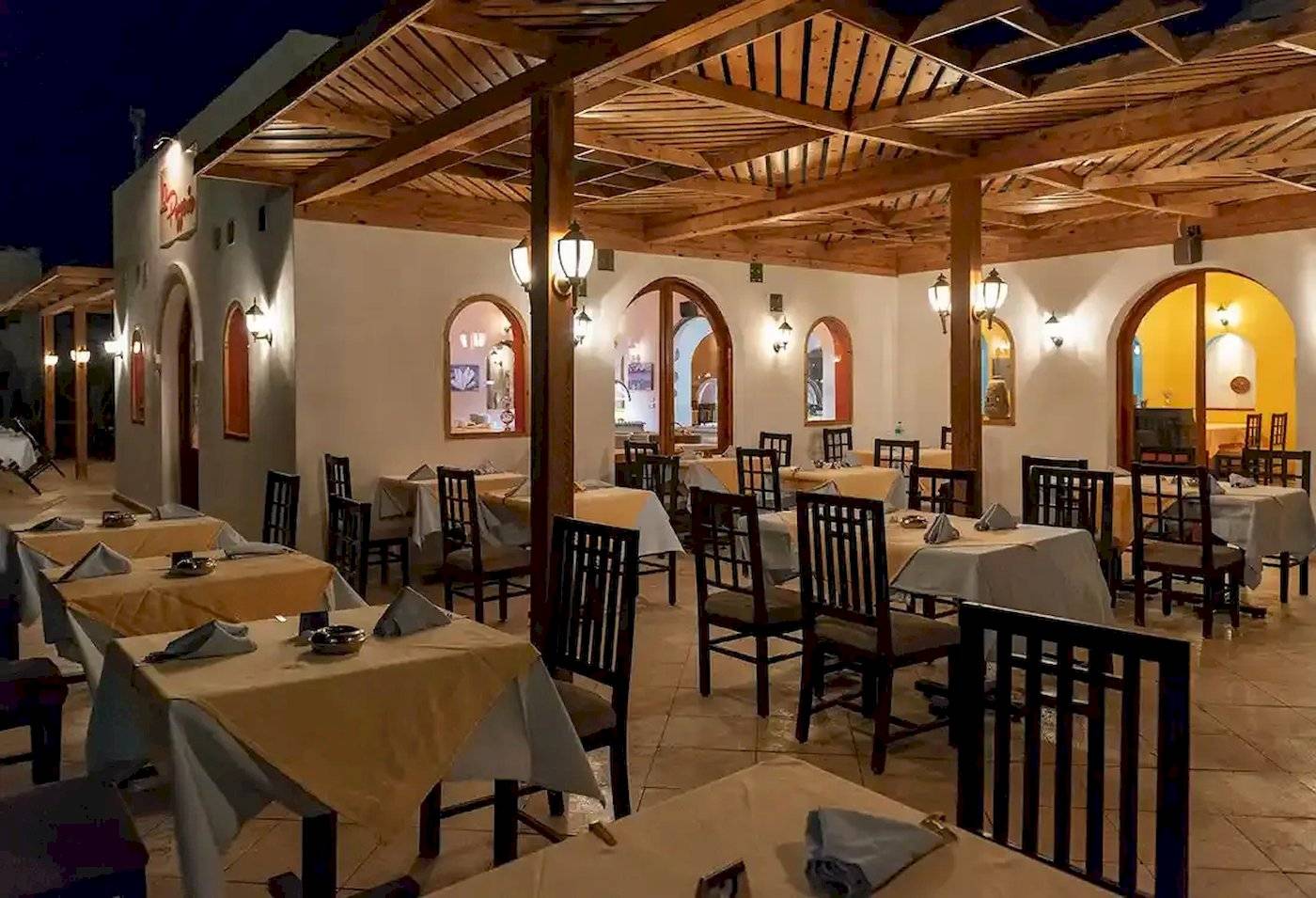 Innenansicht des Restaurants im Gorgonia Beach Resort mit gedeckten Tischen und Holzdecken.