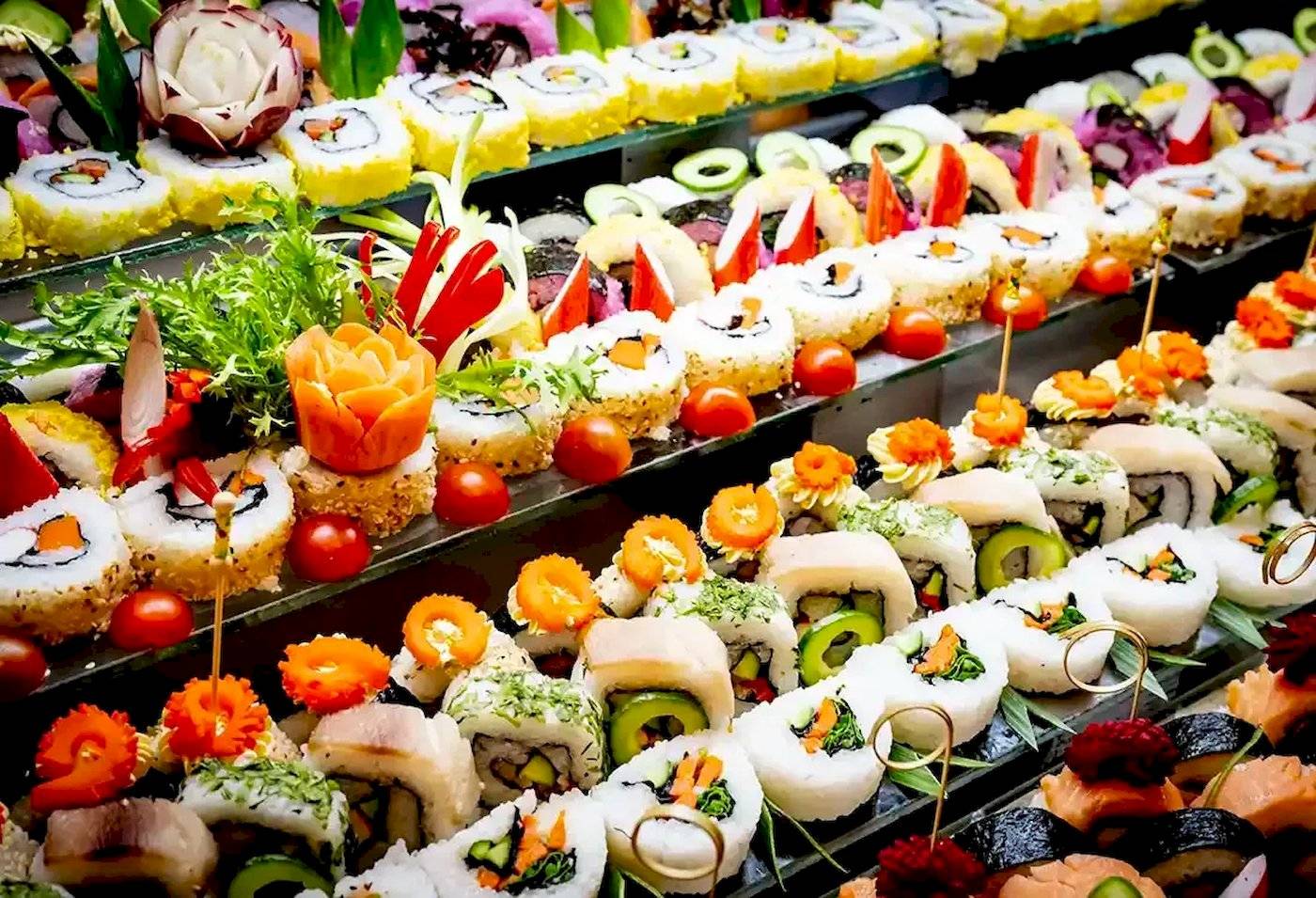 Foto von verschiedenen Sushi-Rollen auf einem Buffet, alle mit verschiedenen Toppings dekoriert.