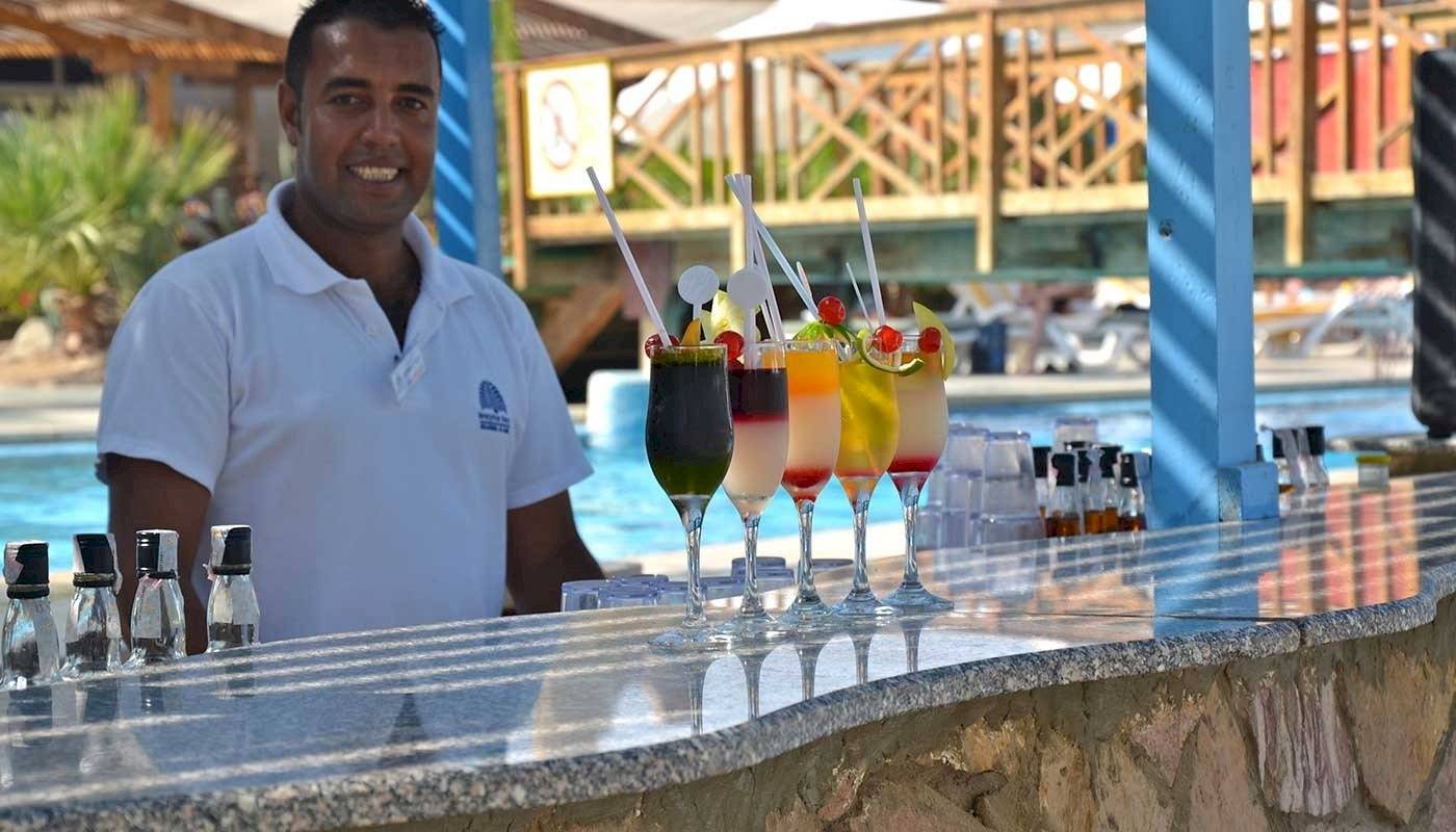Foto von einem Barkeeper im Brayka Bay Resort, der Cocktails an der Poolbar serviert.