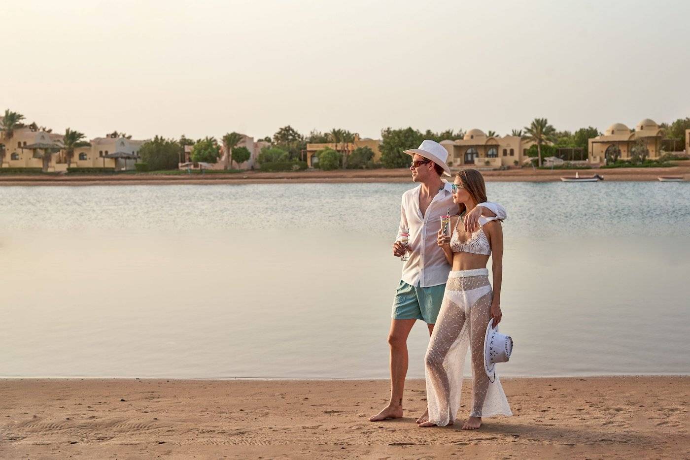 Paar am Strand des Three Corners Rihana Resorts mit Blick auf Wasser und Gebäude