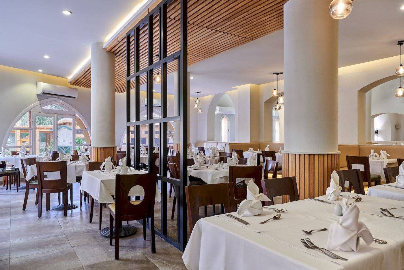 Innenansicht des Restaurants im Three Corners Rihana Resort mit gedeckten Tischen und Stühlen.