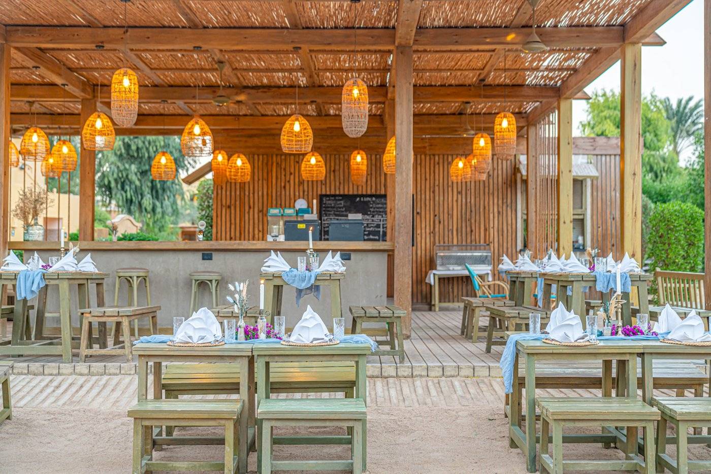 Terrasse des Three Corners Rihana Resorts mit bestuhlten Tischen und hölzerner Überdachung.