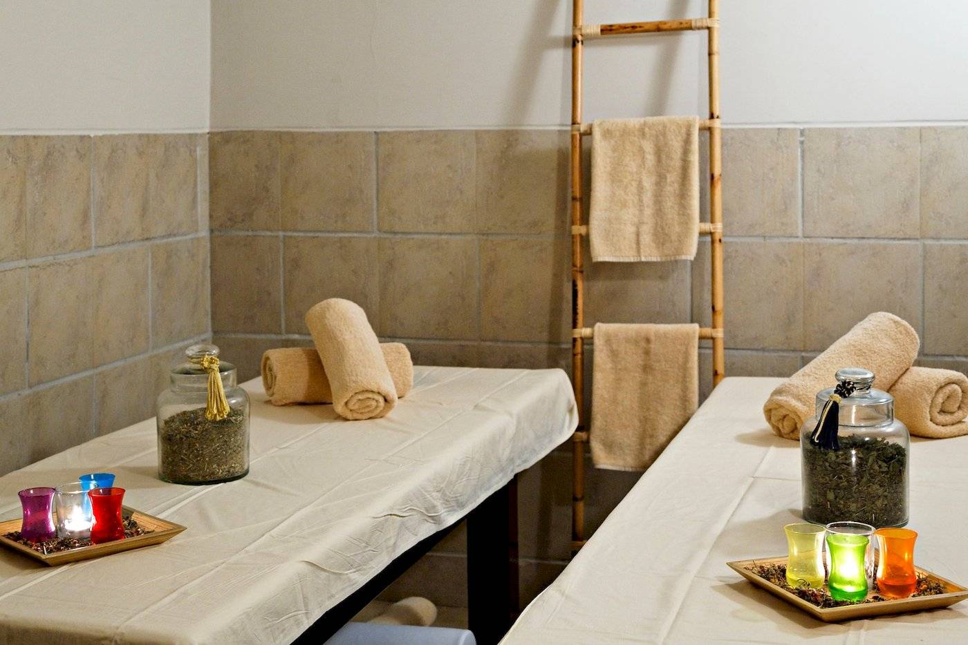 Massageraum im Three Corners Fayrouz Plaza Beach Resort mit zwei Massagetischen, Kerzen und Handtüchern.