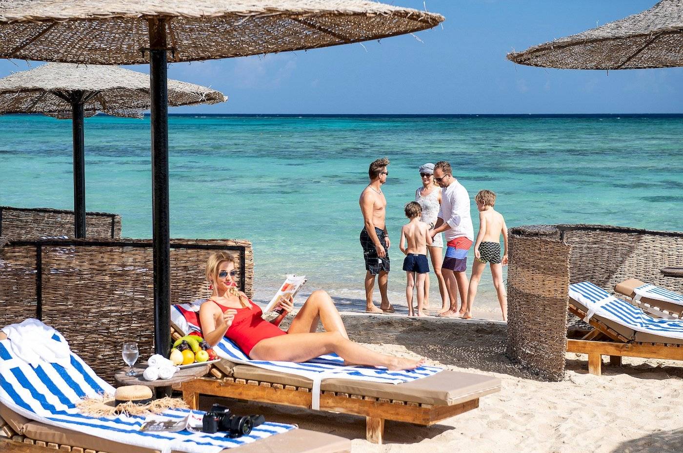 Eine Frau liest ein Buch auf einem Liegestuhl am Strand des Three Corners Fayrouz Plaza Beach Resort.