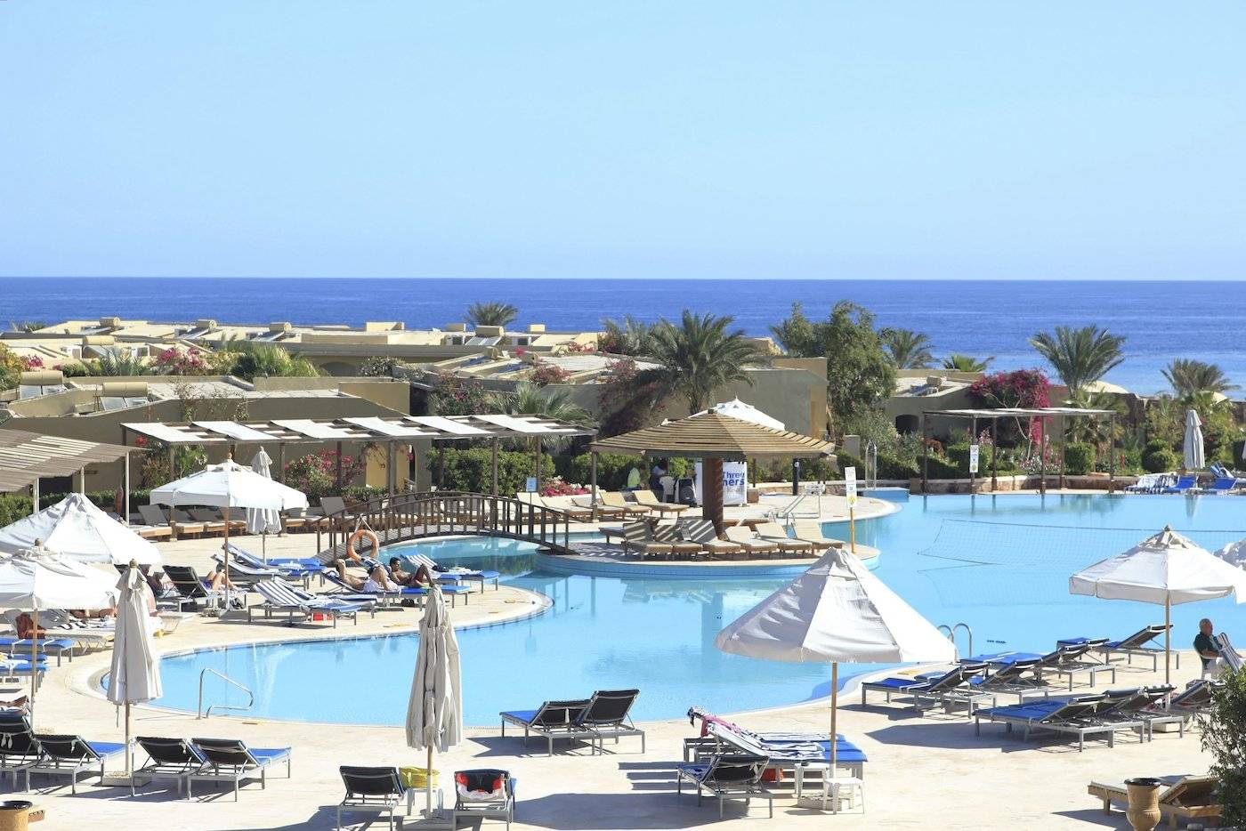 Außenbereich des Three Corners Fayrouz Plaza Beach Resort mit Pool, Liegestühlen und Sonnenschirmen.