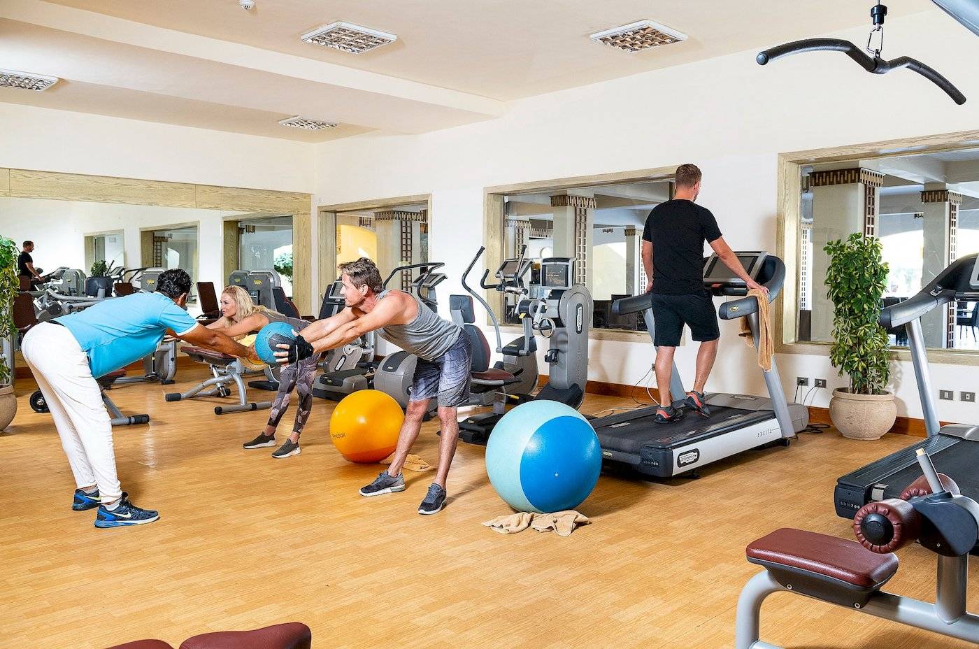 Fitnessstudio im Three Corners Fayrouz Plaza Beach Resort mit Personen, die an Geräten trainieren.