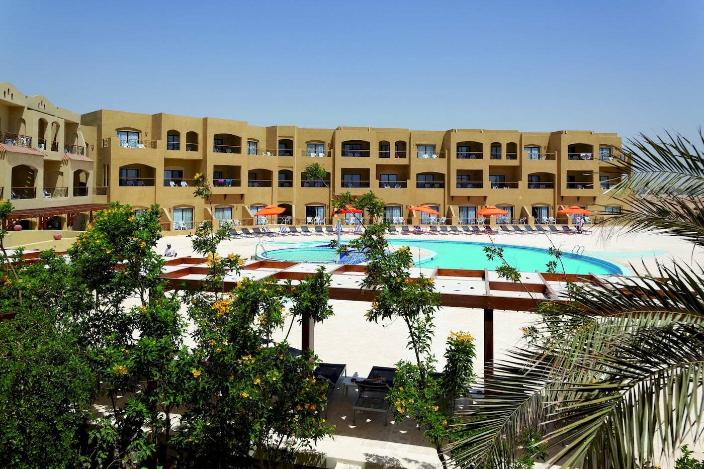 Außenbereich des Three Corners Fayrouz Plaza Beach Resorts mit Swimmingpool und Sonnenschirmen.