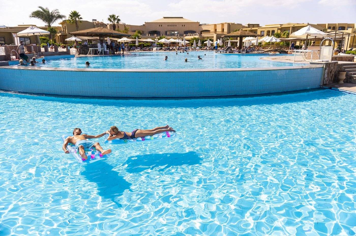 Ein Paar liegt auf Schwimmringen im Pool des Three Corners Fayrouz Plaza Beach Resorts.