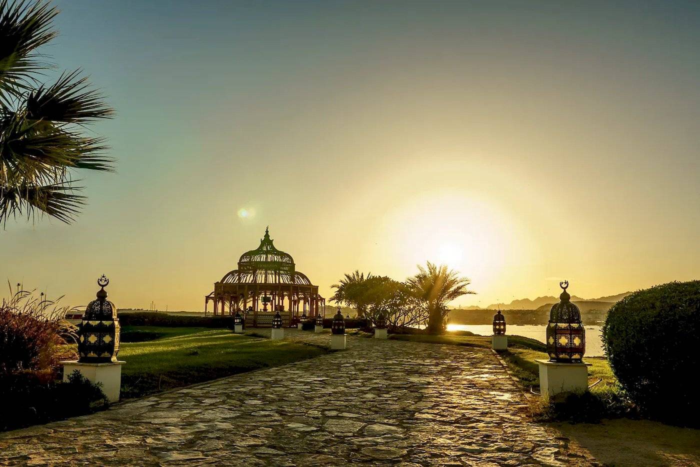 Sonnenuntergang am Mövenpick Resort Sharm el Sheikh mit einem Steinweg und Pavillon im Vordergrund.