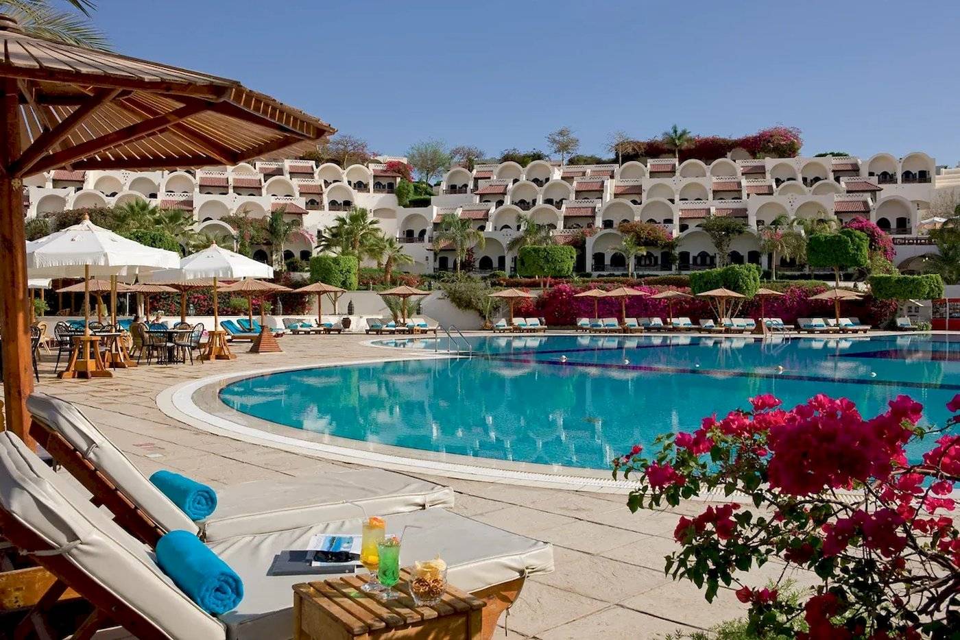 Außenpool des Mövenpick Resort Sharm el Sheikh mit Loungeliegen und Sonnenschirmen