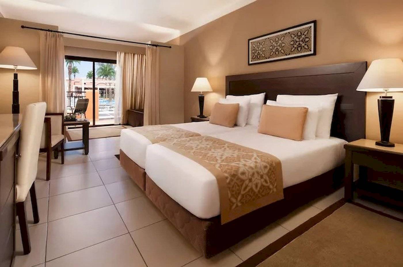 Doppelbett-Zimmer im JAZ Neo Dar El Madina Hotel mit gemusterten Laken, zwei Nachttischen und Lampen.