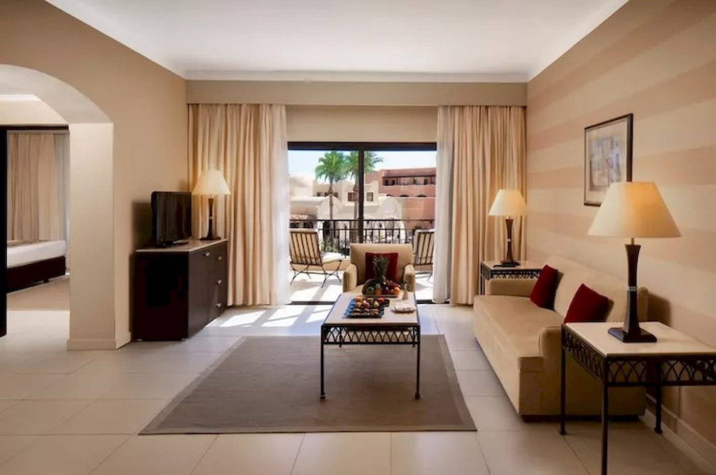 Innenansicht der Suite im JAZ Neo Dar El Madina Hotel mit Wohnzimmer, Couch, Tisch und Balkon.