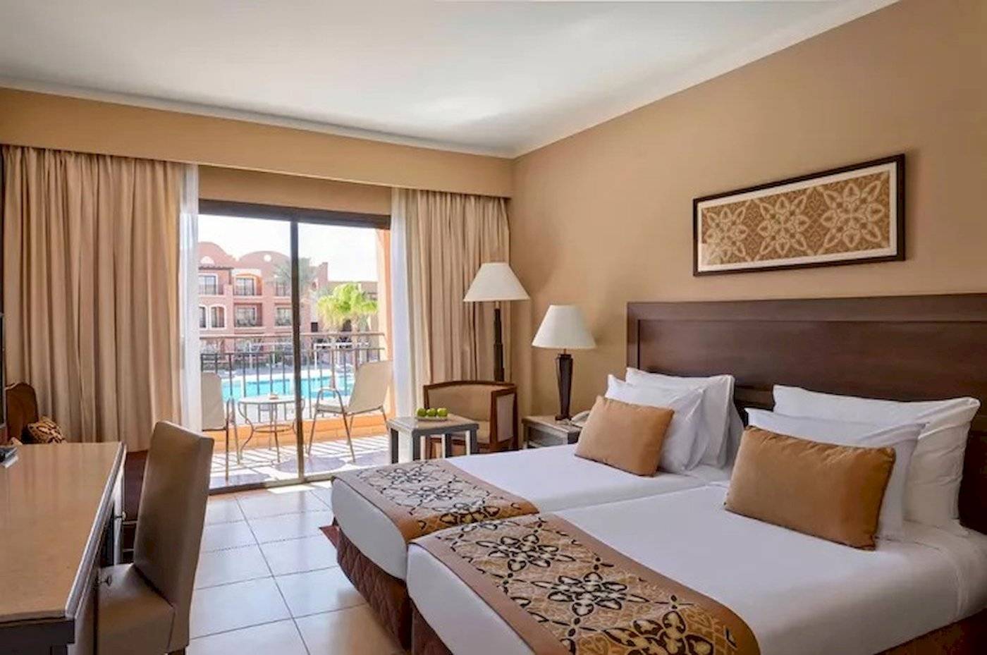 Hotelzimmer mit zwei Betten, Schreibtisch, Stühle, Lampen und Balkon mit Poolblick