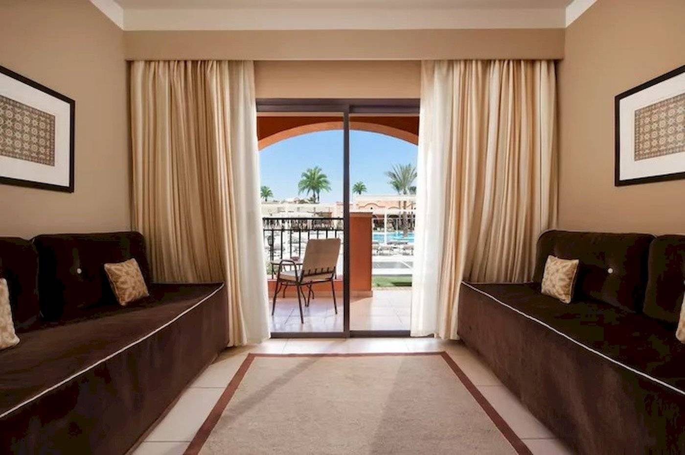 Innenansicht einer Suite im JAZ Neo Dar El Madina Hotel mit Möbeln und Glastür.