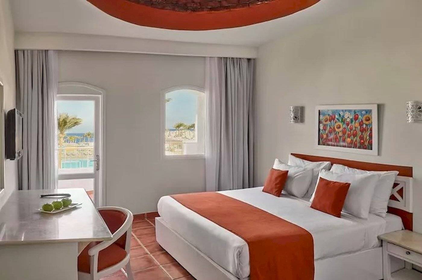 Innenansicht eines Zimmers im Jaz Neo Reef Marsa mit einem Bett, Schreibtisch, Fenster und Meerblick.