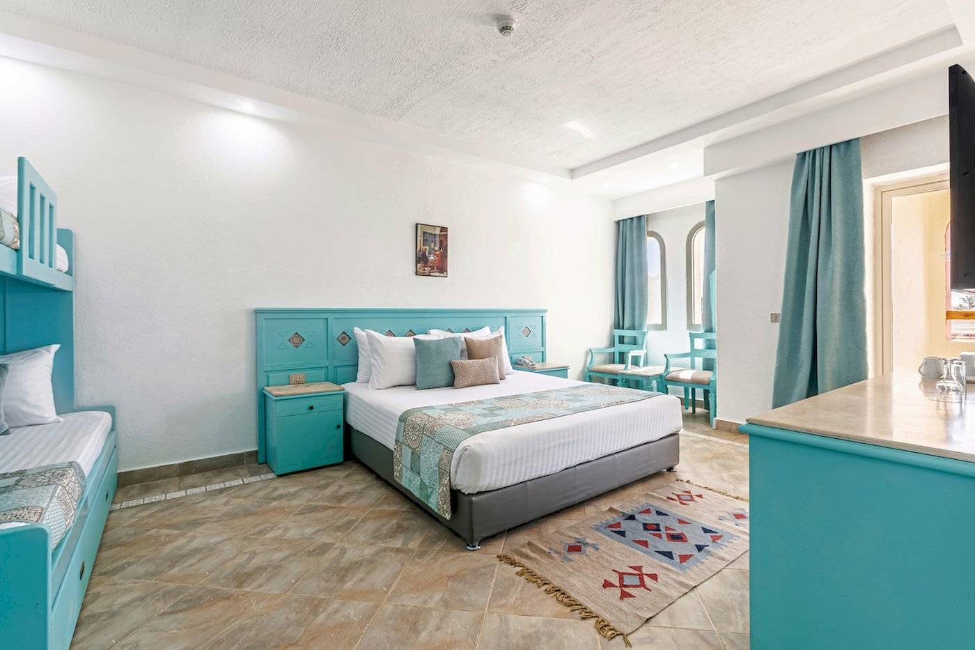 Hotelzimmer im Sunrise Royal Makadi Resort mit Doppelbett, zwei Einzelbetten und grünen Möbeln.
