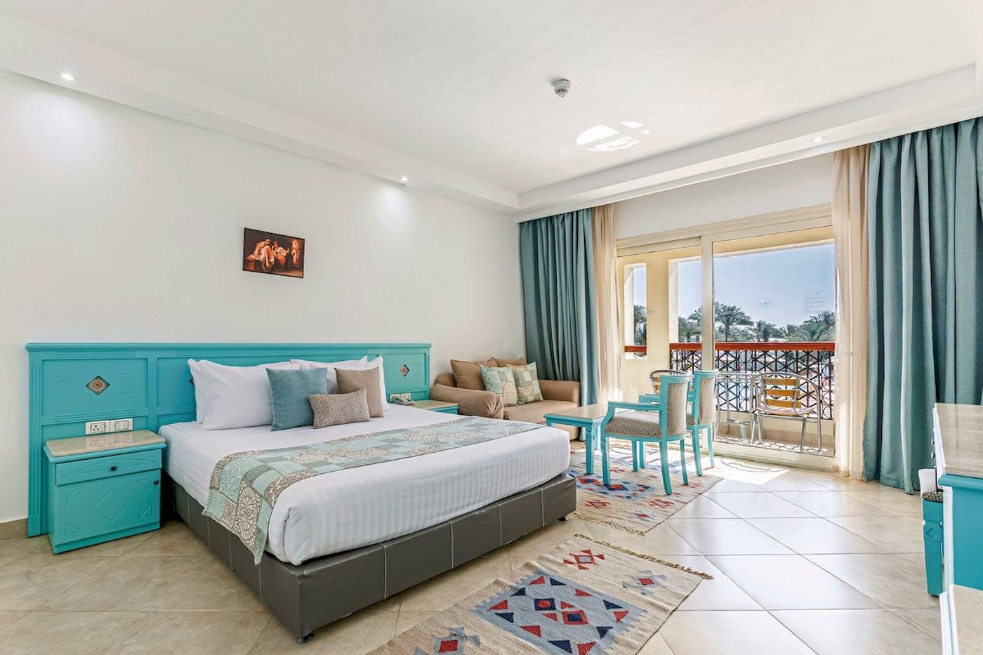 Hotelzimmer im Sunrise Royal Makadi Resort mit Bett, Nachttischen und Balkon.